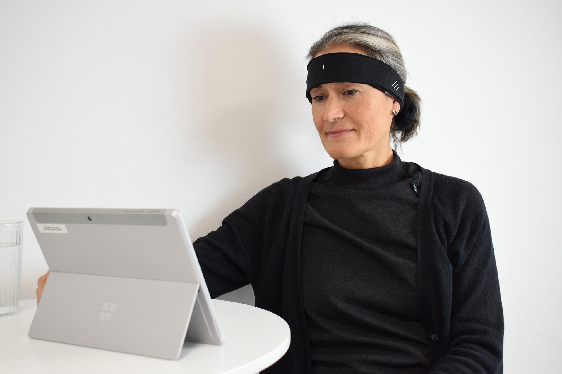 Person using the NeuroBand and the software on a tablet at home.